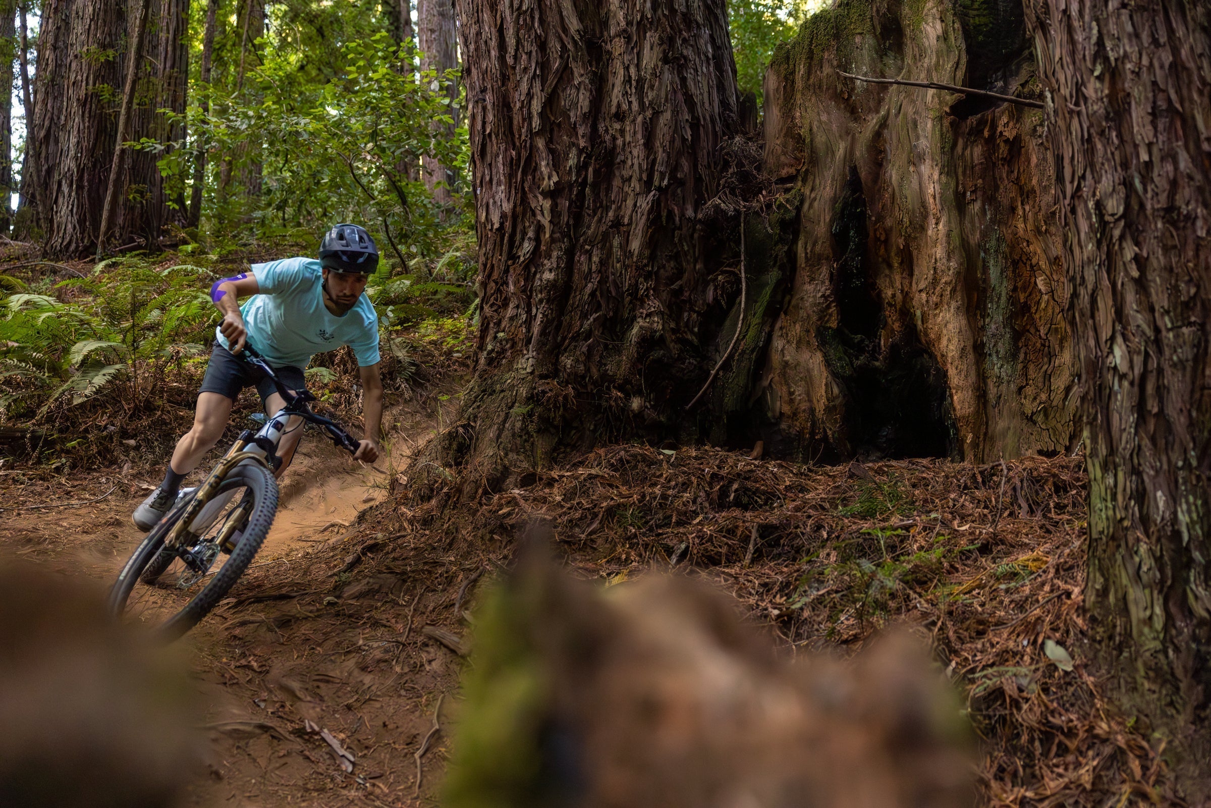 mountain biker rides through trees with kt tape on injuried elbow joint